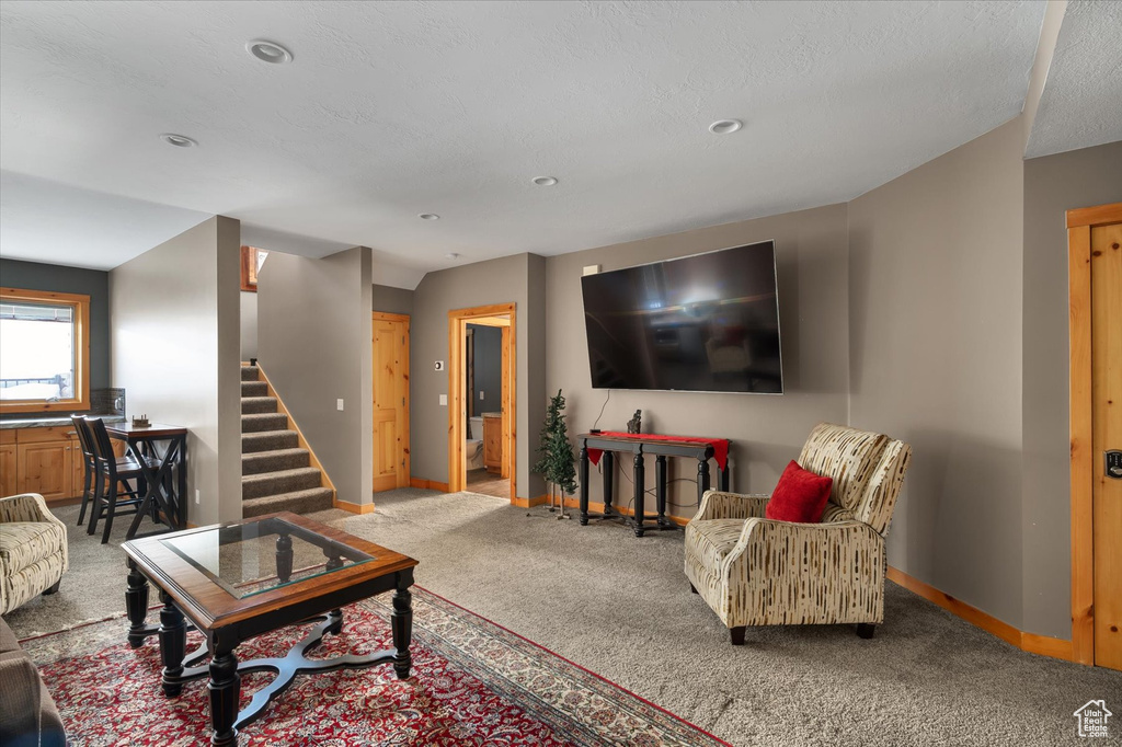 Carpeted living room with baseboards, stairs, and recessed lighting