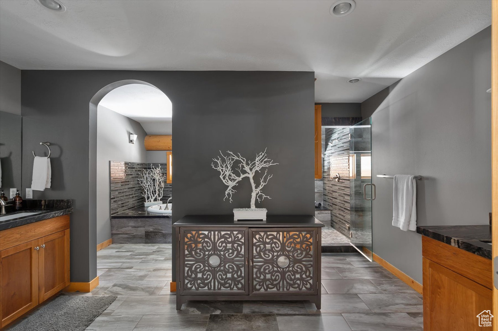 Full bath featuring vanity, baseboards, a stall shower, and a garden tub