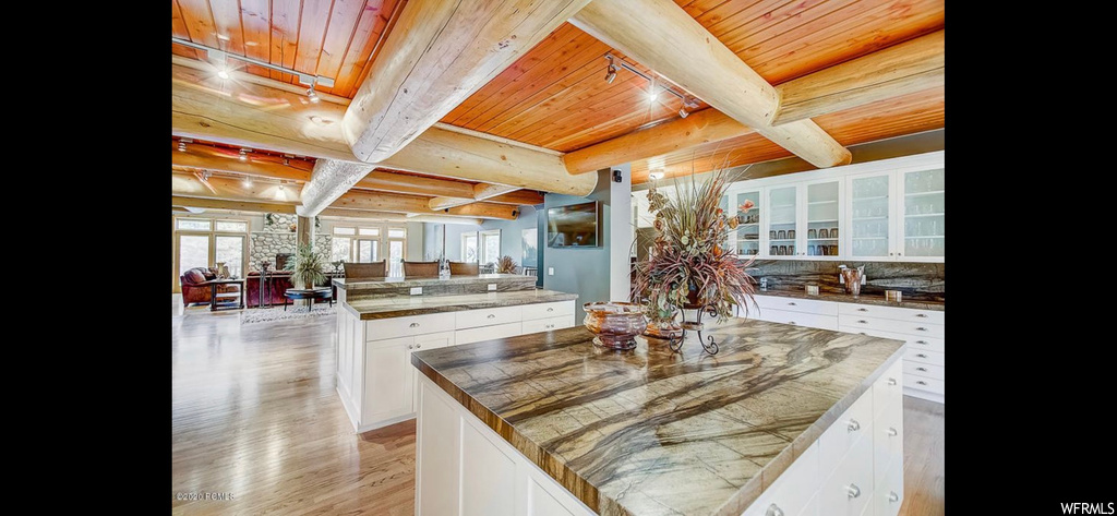 Kitchen featuring a kitchen island, white cabinets, wooden ceiling, and beamed ceiling