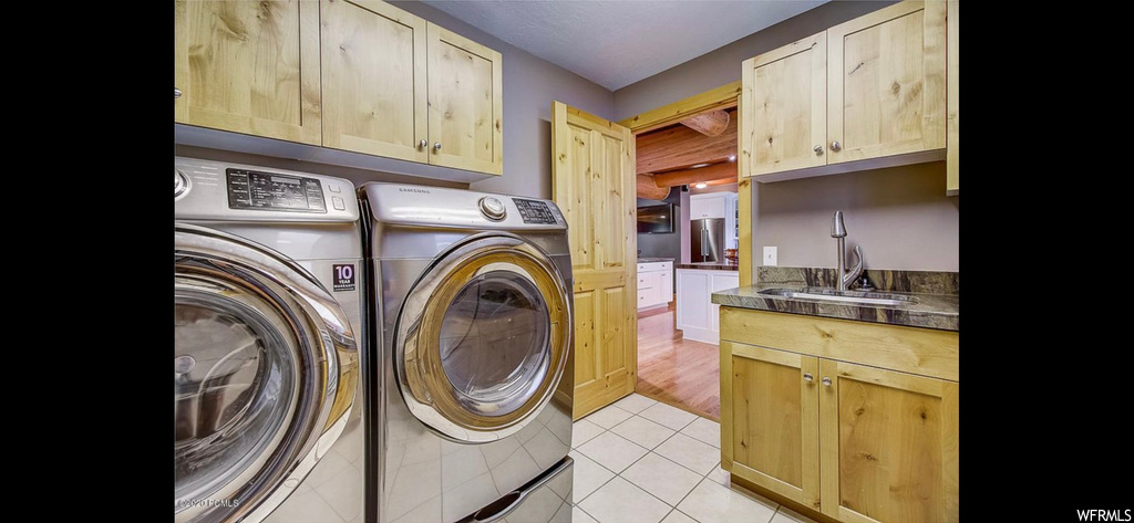 Washroom with separate washer and dryer, sink, cabinets, and light hardwood floors