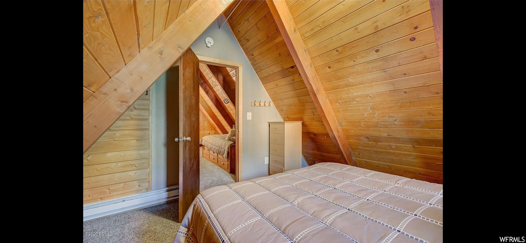 Bedroom with carpet floors, wood ceiling, and wooden walls