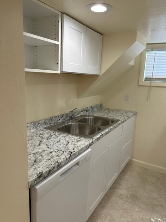 Kitchen featuring sink, white cabinets, light stone countertops, and dishwasher