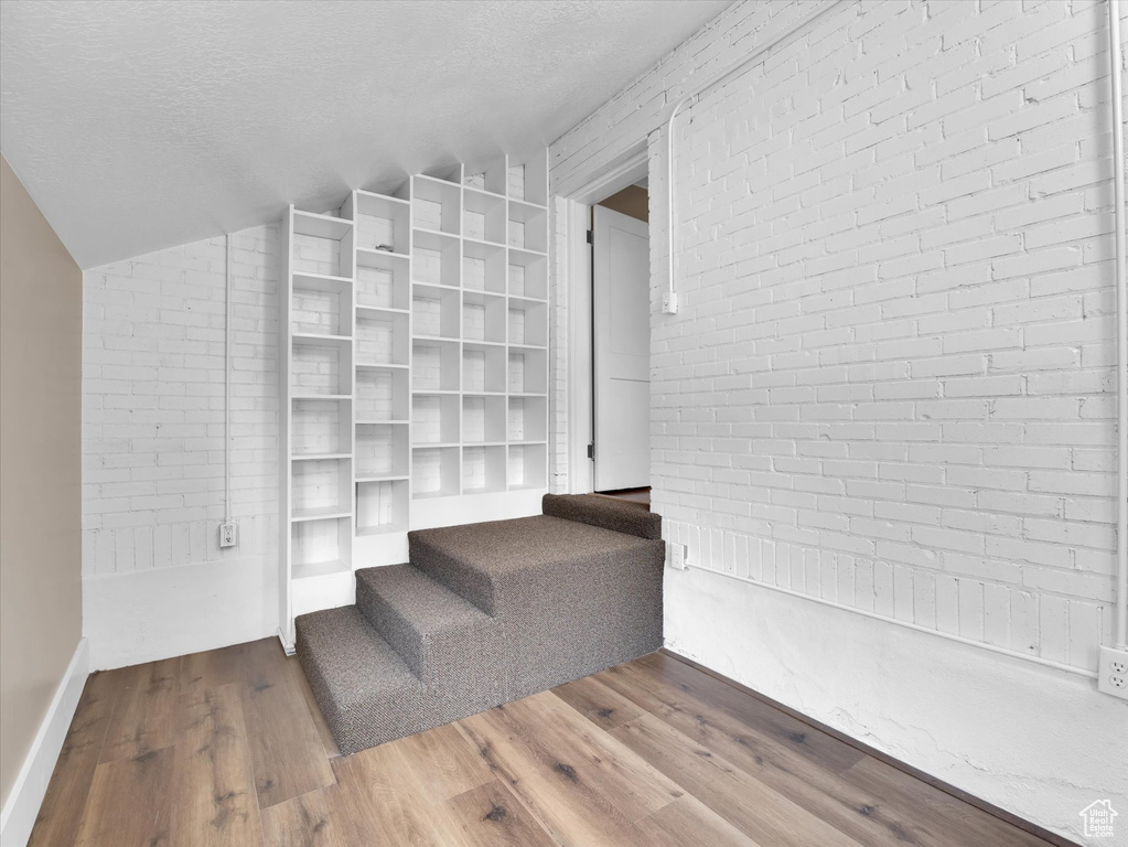 Stairway featuring hardwood / wood-style flooring, a textured ceiling, and lofted ceiling