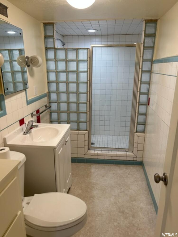 Bathroom featuring an enclosed shower, toilet, vanity, and backsplash