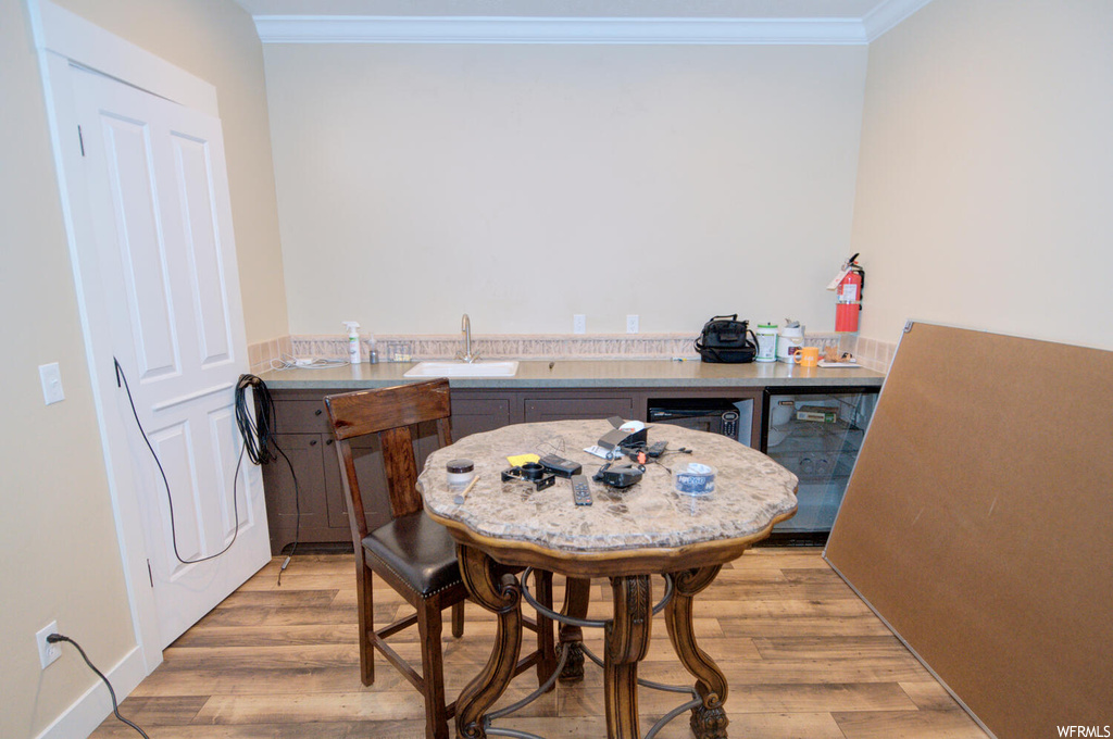 Hardwood floored dining space with crown molding and sink