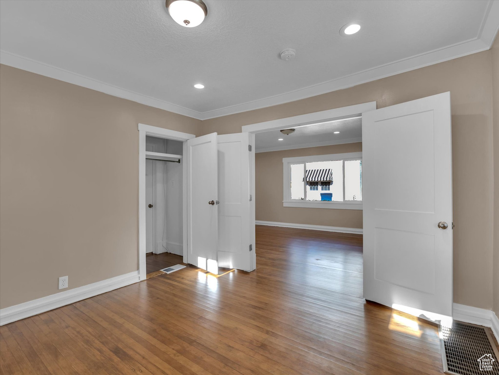Empty room with crown molding and hardwood / wood-style flooring