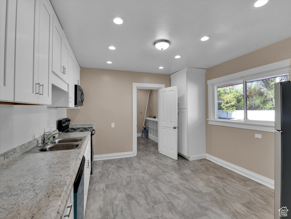 Kitchen featuring sink, appliances with stainless steel finishes, white cabinets, and light tile floors
