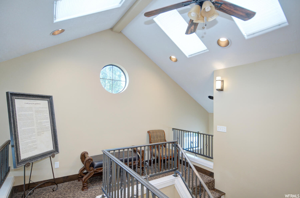 Staircase with vaulted ceiling high, a skylight, ceiling fan, and beamed ceiling