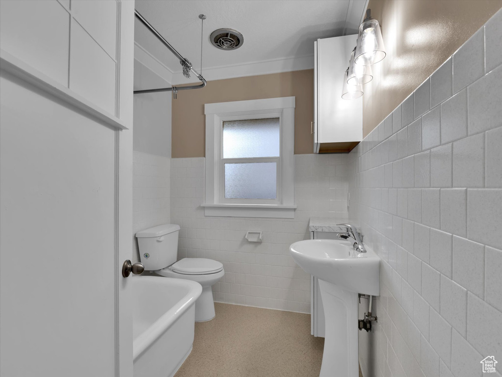 Bathroom with tasteful backsplash, toilet, tile walls, and sink