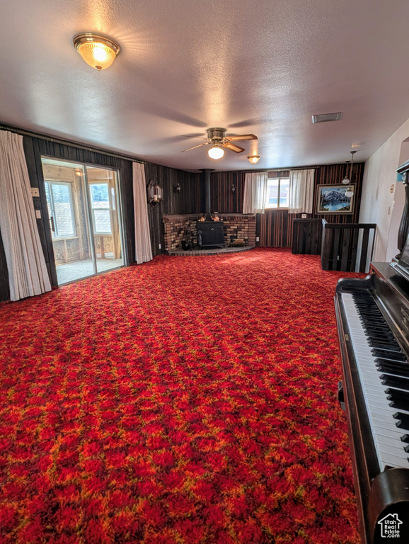 Living room featuring a wood stove, a textured ceiling, a wealth of natural light, and carpet floors