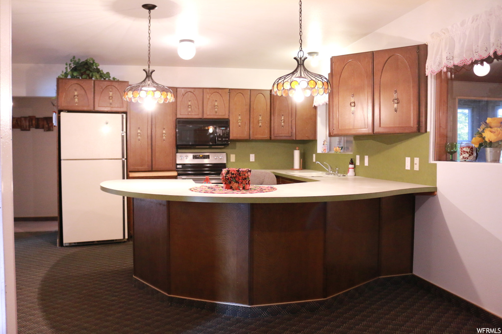 Kitchen with range, pendant lighting, dark colored carpet, and white refrigerator