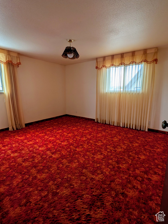 Carpeted spare room featuring a textured ceiling
