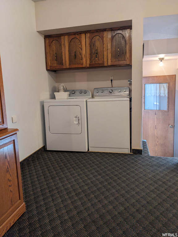 Clothes washing area with dark carpet, cabinets, and separate washer and dryer