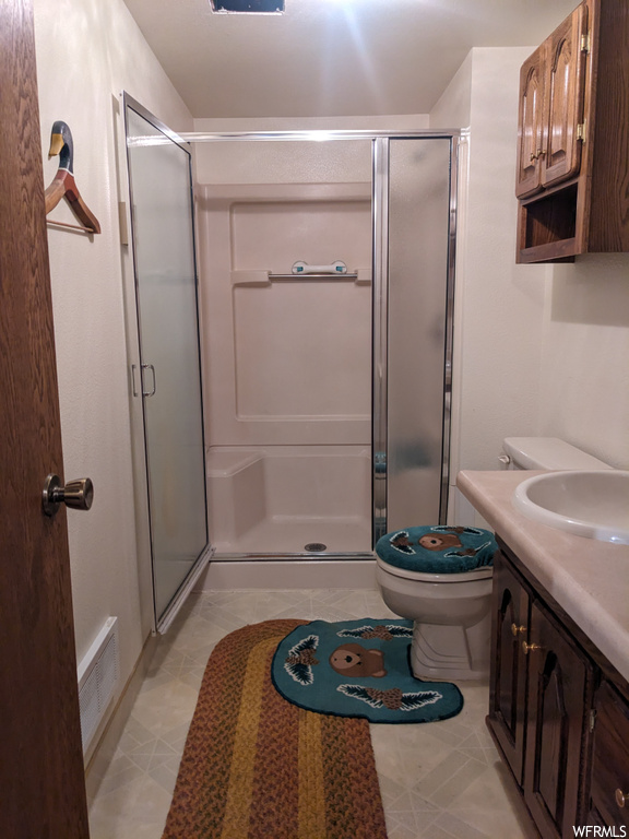Bathroom featuring walk in shower, tile floors, toilet, and vanity