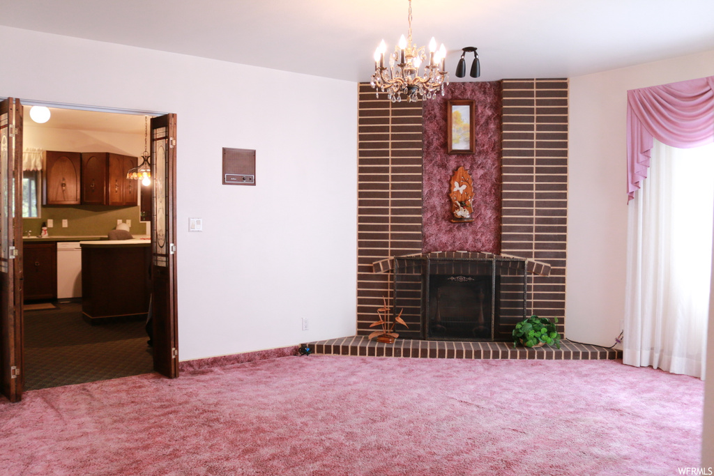 Living room featuring light colored carpet, a fireplace, and an inviting chandelier