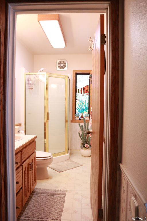 Bathroom featuring tile floors, an enclosed shower, vanity, and toilet