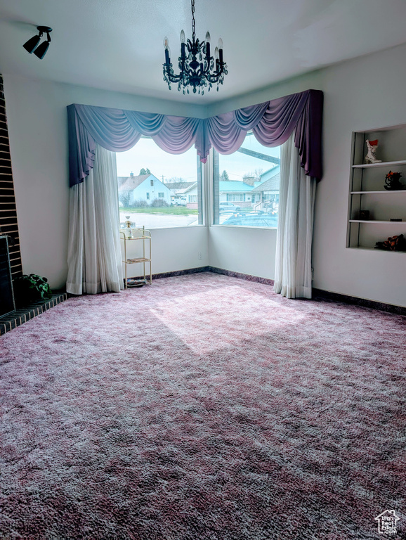 Unfurnished dining area with a notable chandelier, carpet flooring, and baseboards