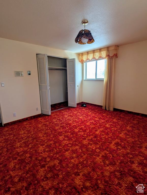 Unfurnished bedroom with a closet, baseboards, carpet, and a textured ceiling