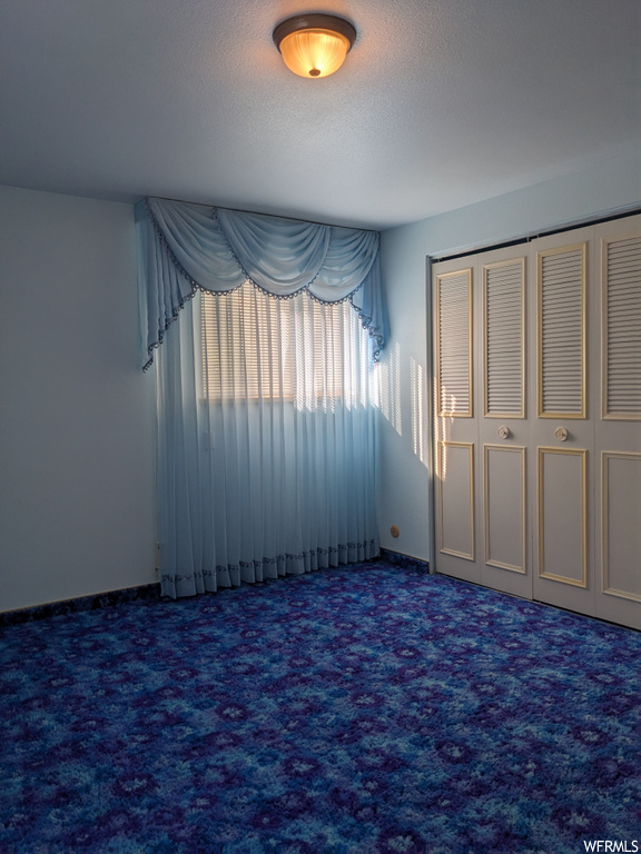 Unfurnished bedroom featuring a textured ceiling, a closet, and carpet floors