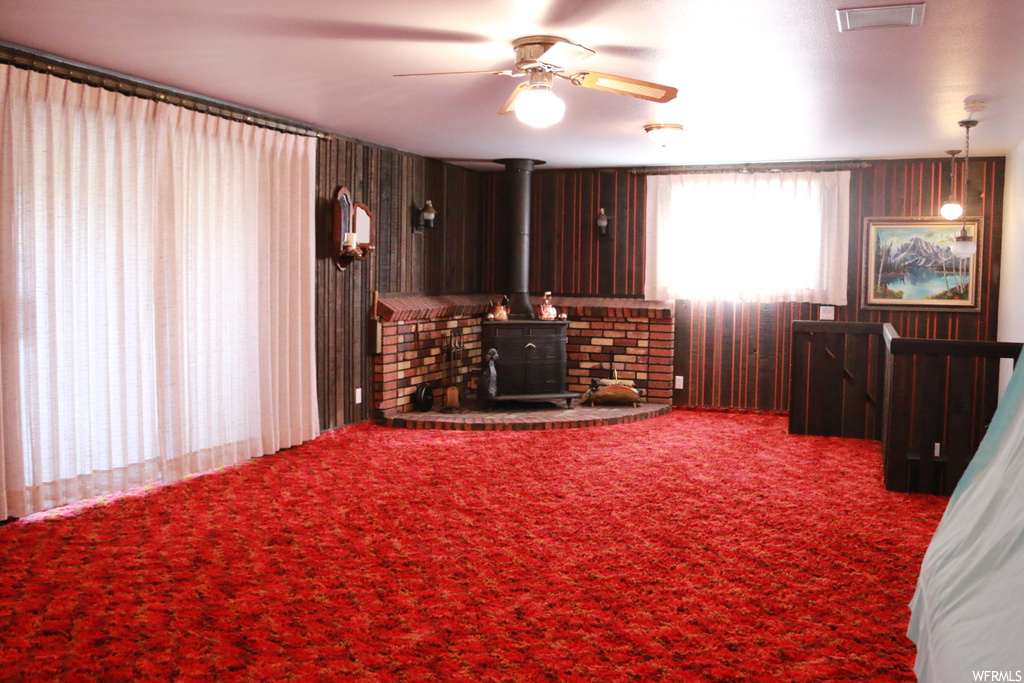 Living room with ceiling fan, a wood stove, and carpet
