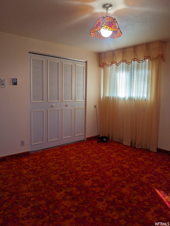 Unfurnished bedroom with a textured ceiling, a closet, and carpet floors