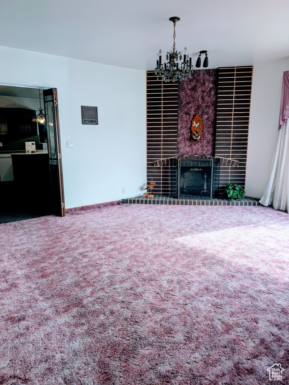 Living room featuring a notable chandelier, a fireplace, and carpet flooring