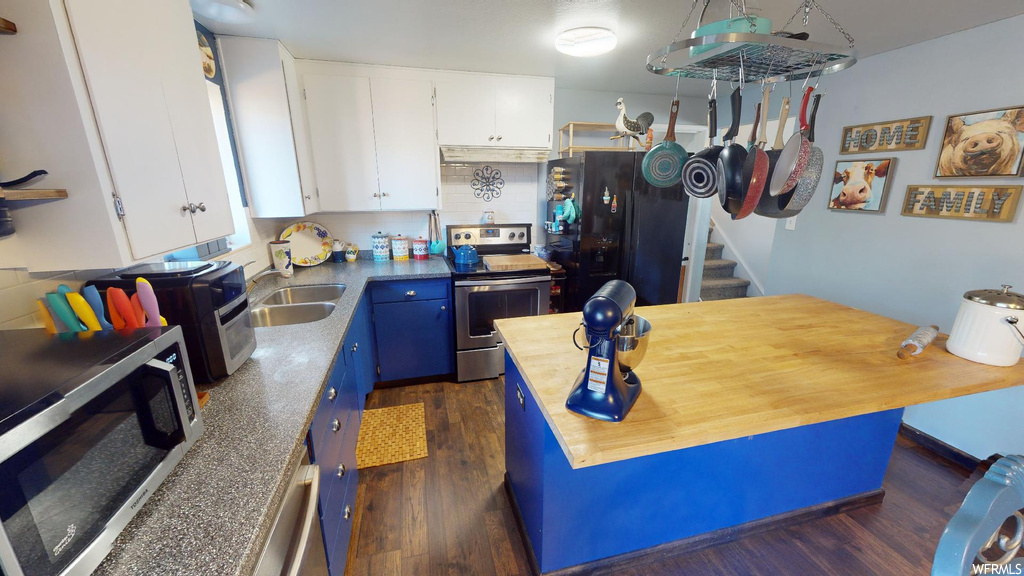 Kitchen featuring sink, white cabinets, blue cabinets, stainless steel appliances, and dark hardwood floors