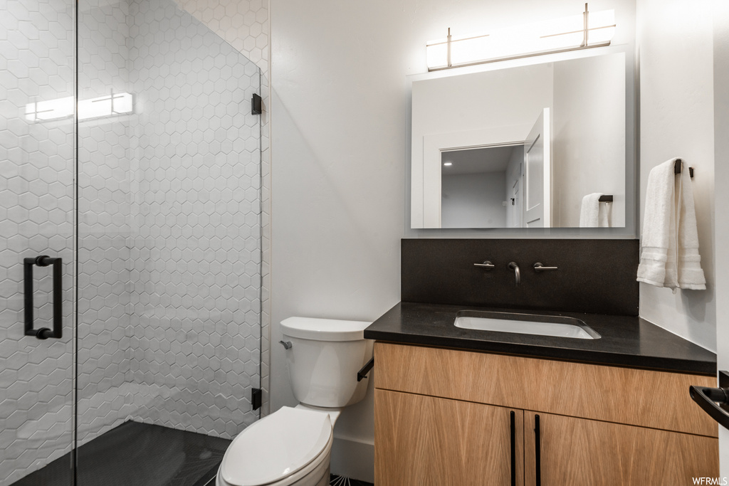 Bathroom featuring vanity, an enclosed shower, and toilet