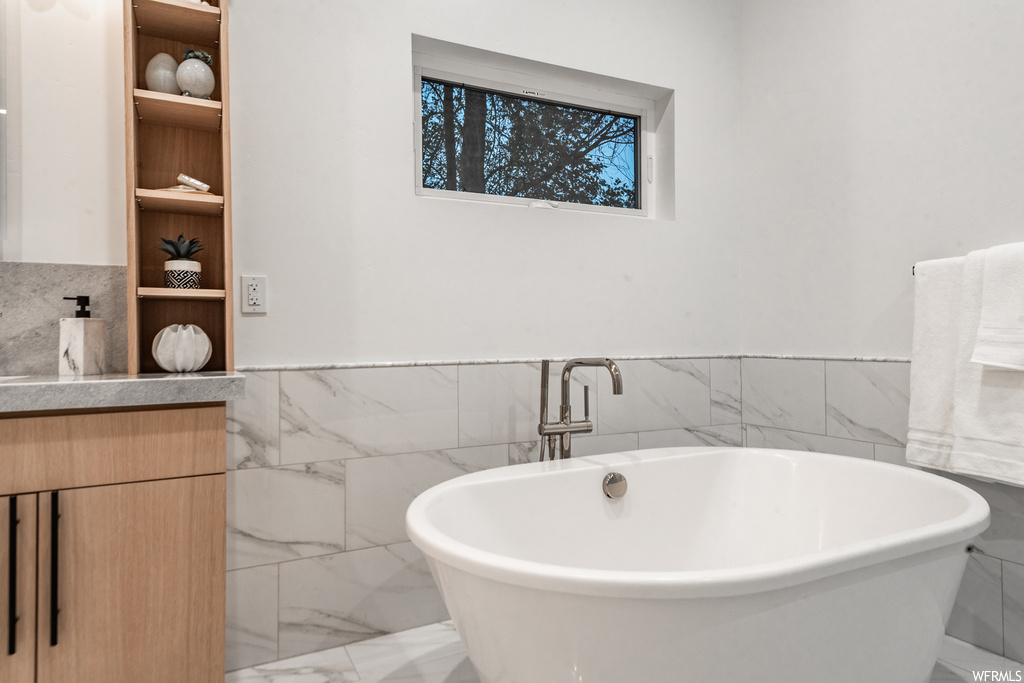Bathroom with a bathing tub, tile walls, vanity, and tile floors