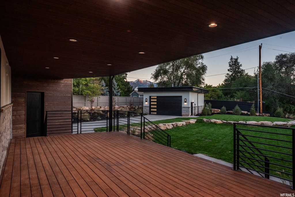 Deck at dusk featuring a yard and a garage