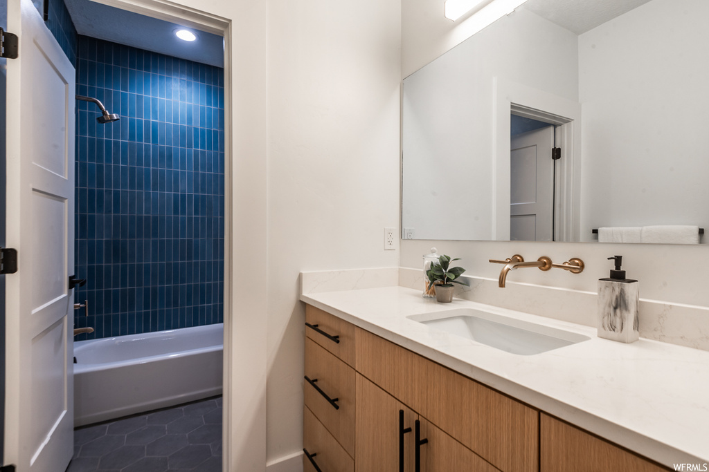 Bathroom featuring tile floors, large vanity, and tiled shower / bath