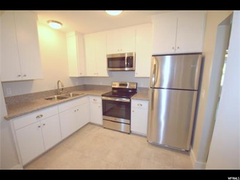 Kitchen with light tile floors, white cabinets, and appliances with stainless steel finishes