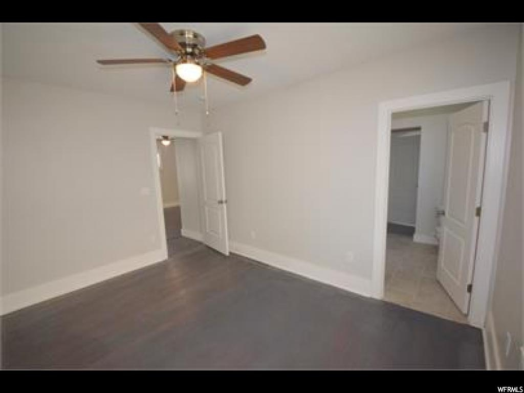 Empty room with ceiling fan and dark hardwood floors