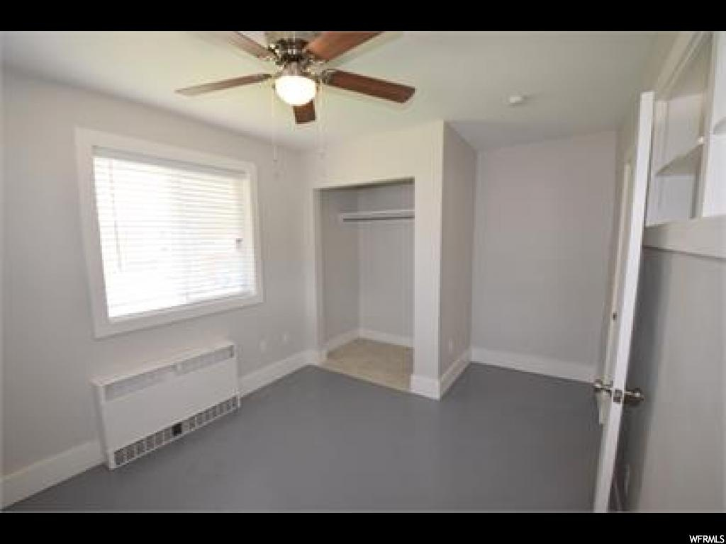 Unfurnished bedroom featuring ceiling fan, a closet, and radiator heating unit