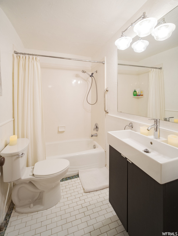 Full bathroom with toilet, shower / tub combo with curtain, vanity, and tile flooring