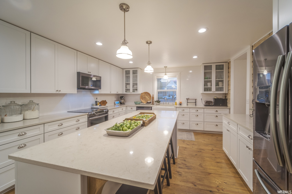 Kitchen with a center island, white cabinets, and appliances with stainless steel finishes