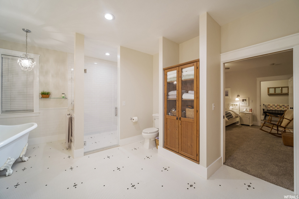 Bathroom featuring an inviting chandelier, toilet, and plus walk in shower