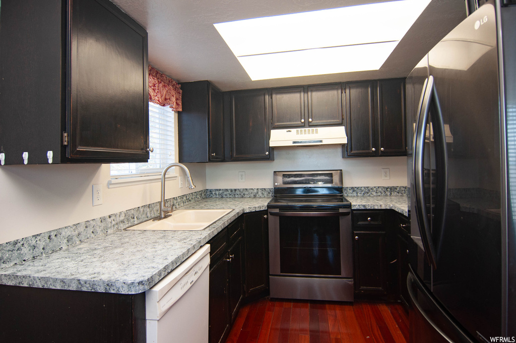 Kitchen featuring stainless steel range with electric stovetop, dark hardwood floors, black fridge, sink, and white dishwasher