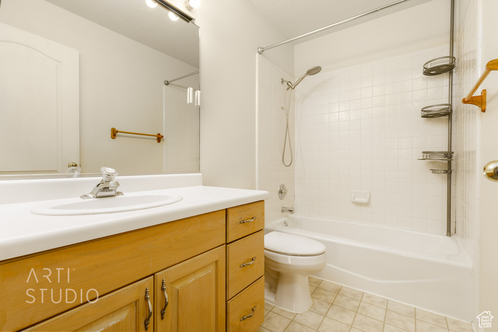 Full bathroom with tiled shower / bath combo, vanity, tile flooring, and toilet