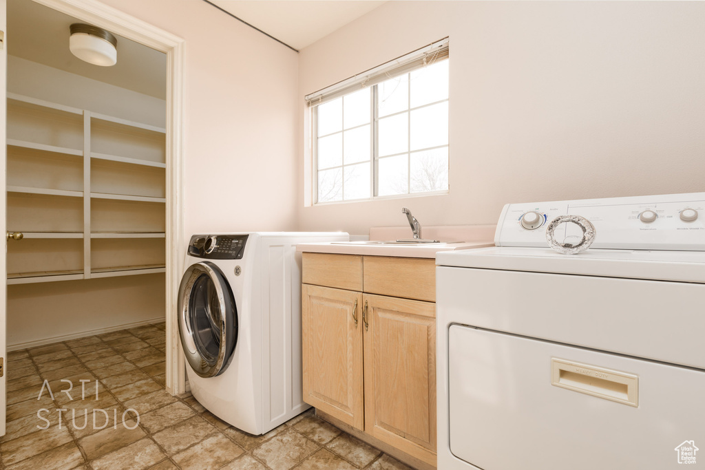 Laundry room with washer and clothes dryer, light tile floors, cabinets, and sink