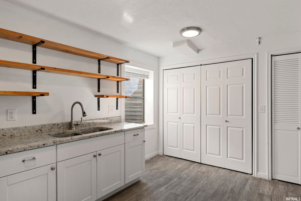 Kitchen featuring white cabinets, dark hardwood flooring, and sink