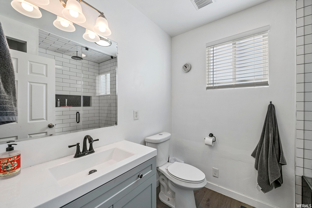 Bathroom featuring toilet, hardwood floors, and vanity with extensive cabinet space