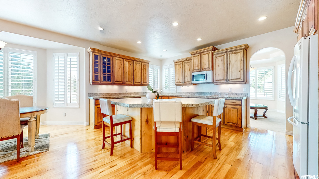 Kitchen featuring white appliances, a kitchen breakfast bar, light hardwood / wood-style floors, and a center island