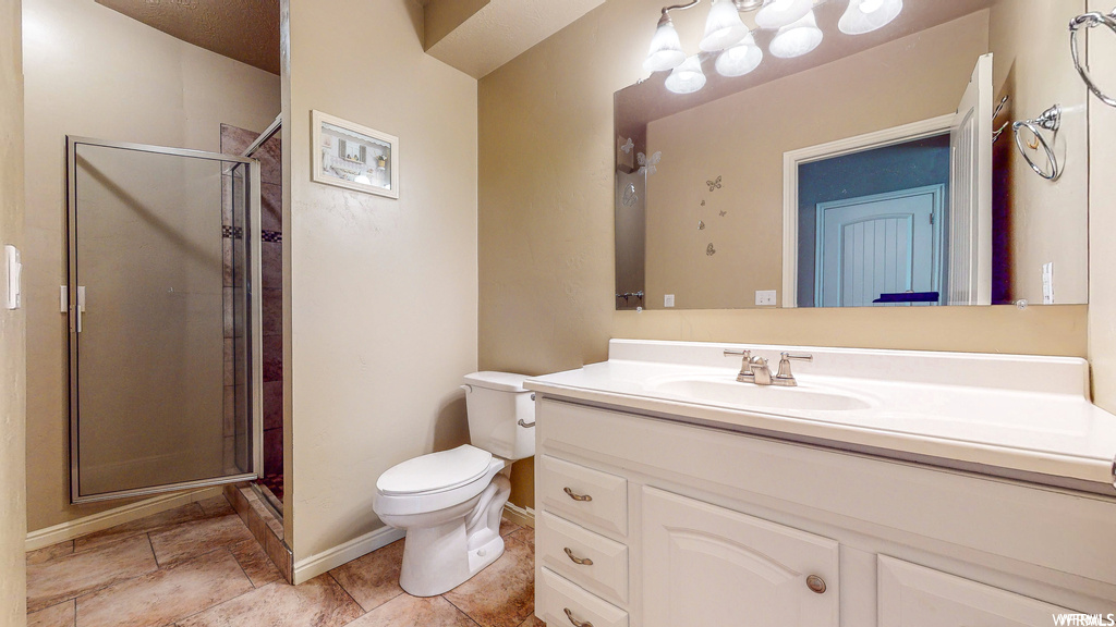 Bathroom featuring tile flooring, an enclosed shower, toilet, and vanity with extensive cabinet space
