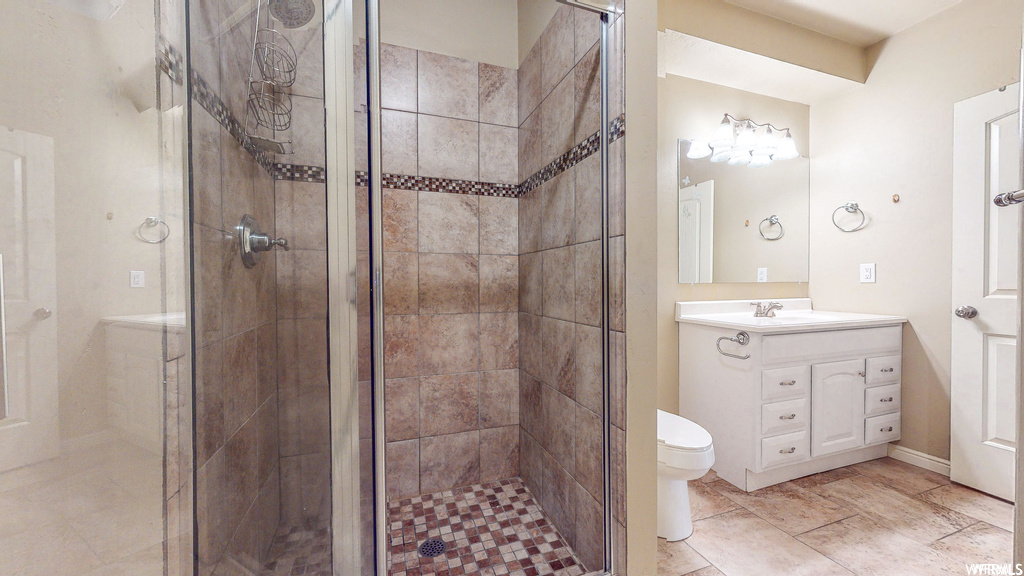 Bathroom with tile flooring, a shower with door, toilet, and vanity