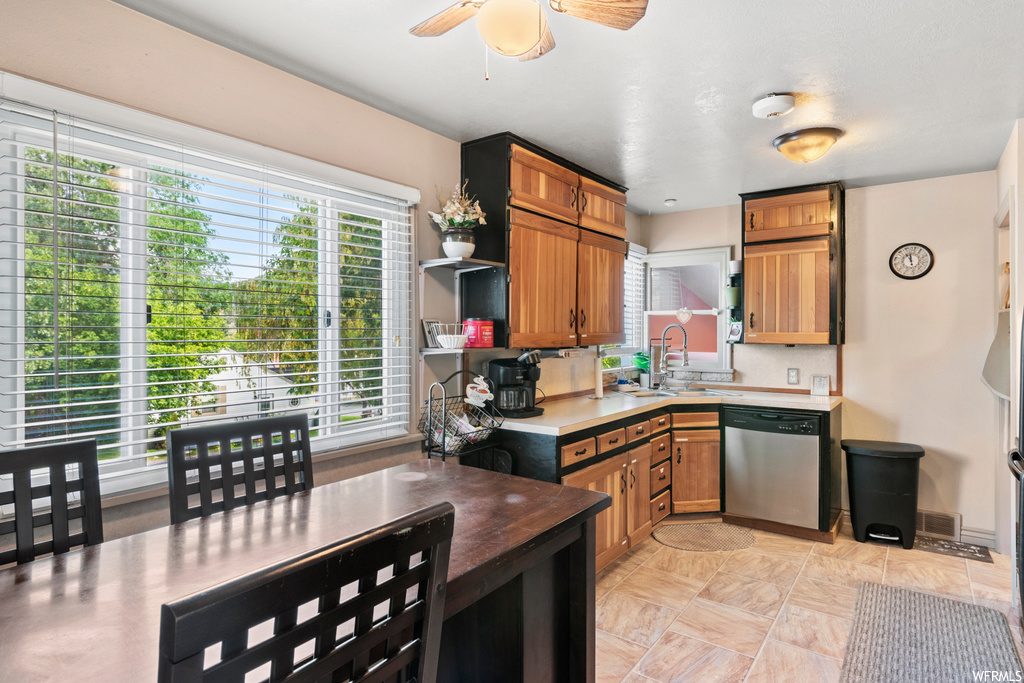Kitchen featuring stainless steel dishwasher, light tile flooring, a wealth of natural light, and ceiling fan