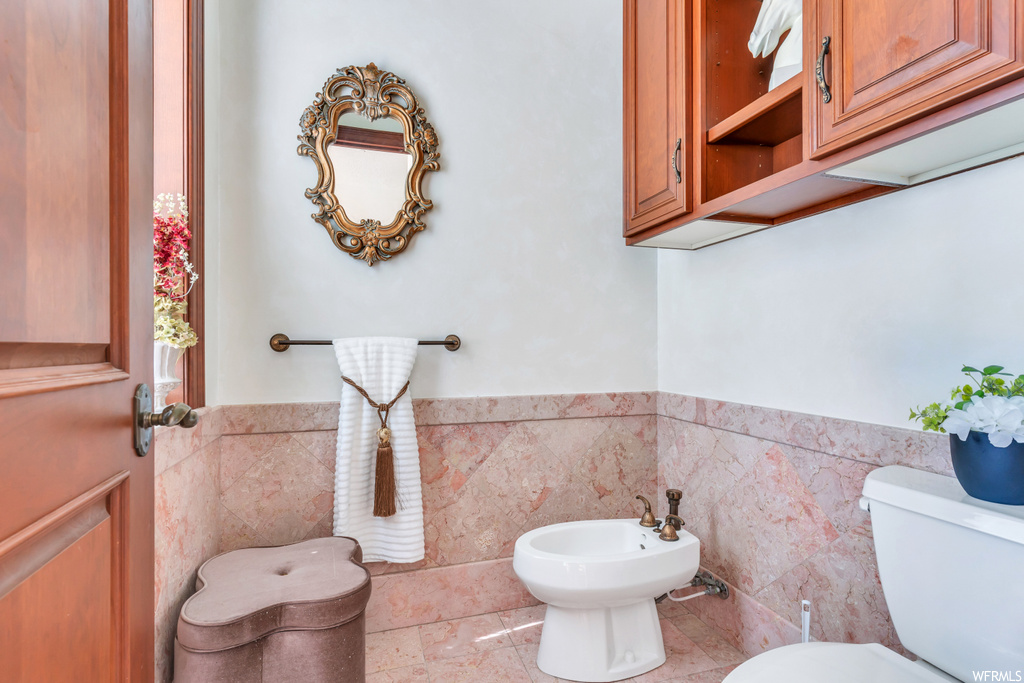 Bathroom featuring tile walls, a bidet, tile flooring, and toilet