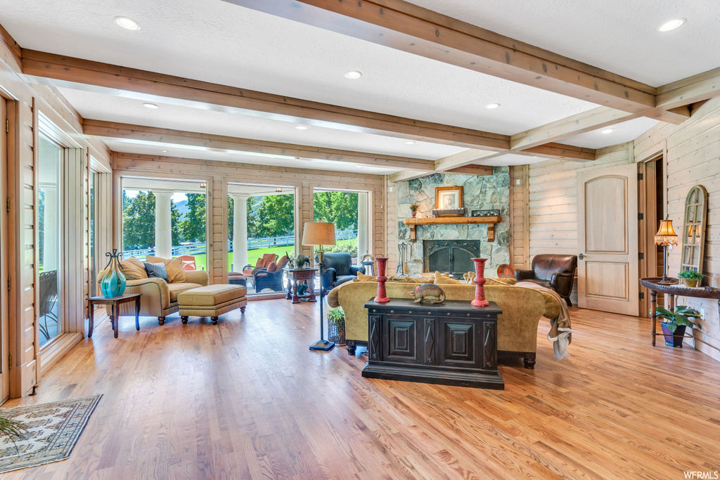 Hardwood floored living room with beam ceiling and a stone fireplace