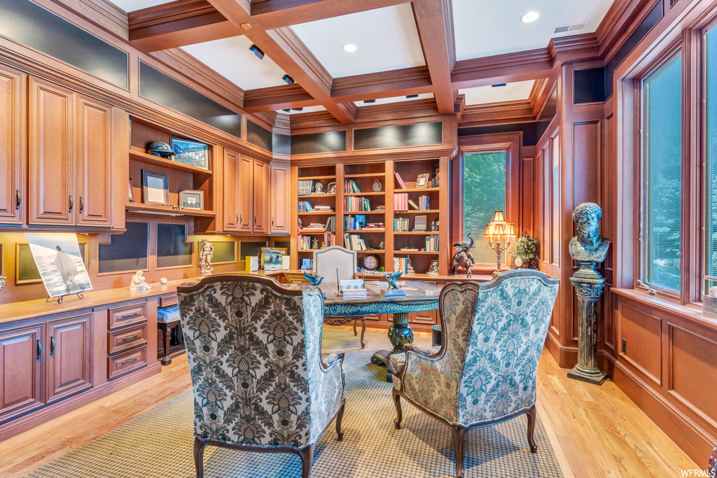 Office space with coffered ceiling, a wealth of natural light, light hardwood flooring, and built in desk