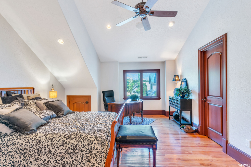 Bedroom with vaulted ceiling, light hardwood floors, and ceiling fan